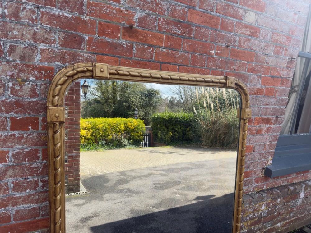 A large 19th-century English giltwood overmantel mirror featuring a carved rope twist frame with rounded top corners and acanthus leaf base scrolls. View II