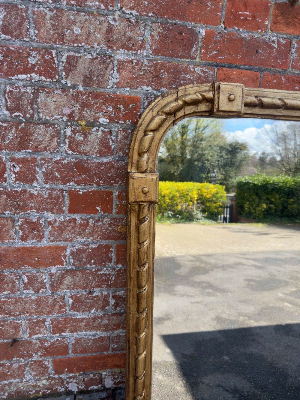 A large 19th-century English giltwood overmantel mirror featuring a carved rope twist frame with rounded top corners and acanthus leaf base scrolls. View V