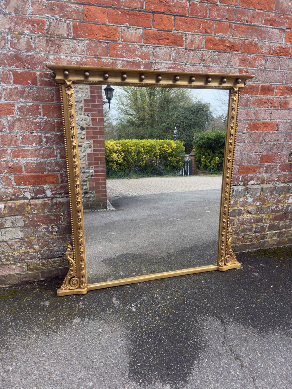 A large 19th-century rectangular giltwood and gesso overmantel mirror featuring a row of decorative spherules beneath the upper cornice and scrolled side feet.