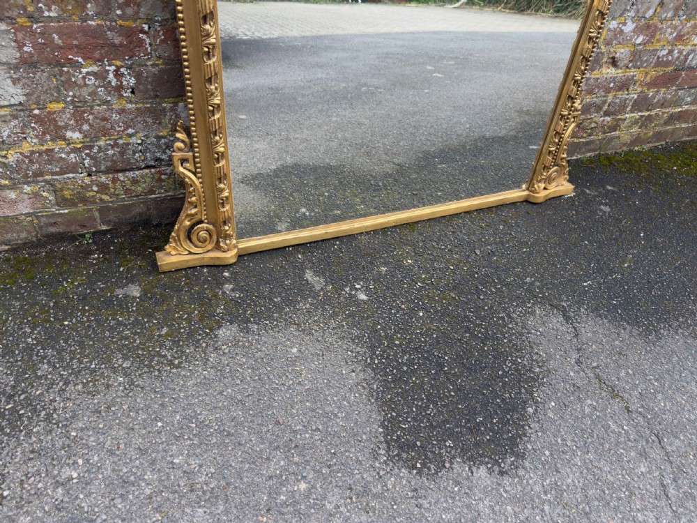 A large 19th-century rectangular giltwood and gesso overmantel mirror featuring a row of decorative spherules beneath the upper cornice and scrolled side feet. View V