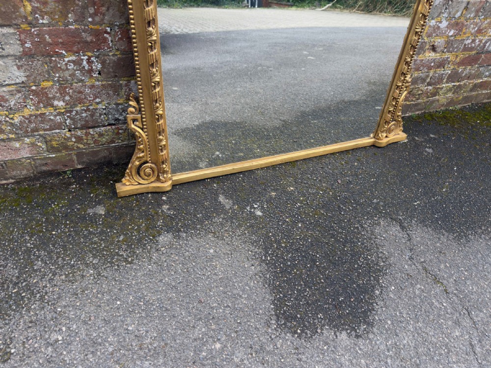 A nineteenth-century giltwood overmantel mirror with detailed gesso moulding, corner spandrels, and a central carved floral cresting. View III