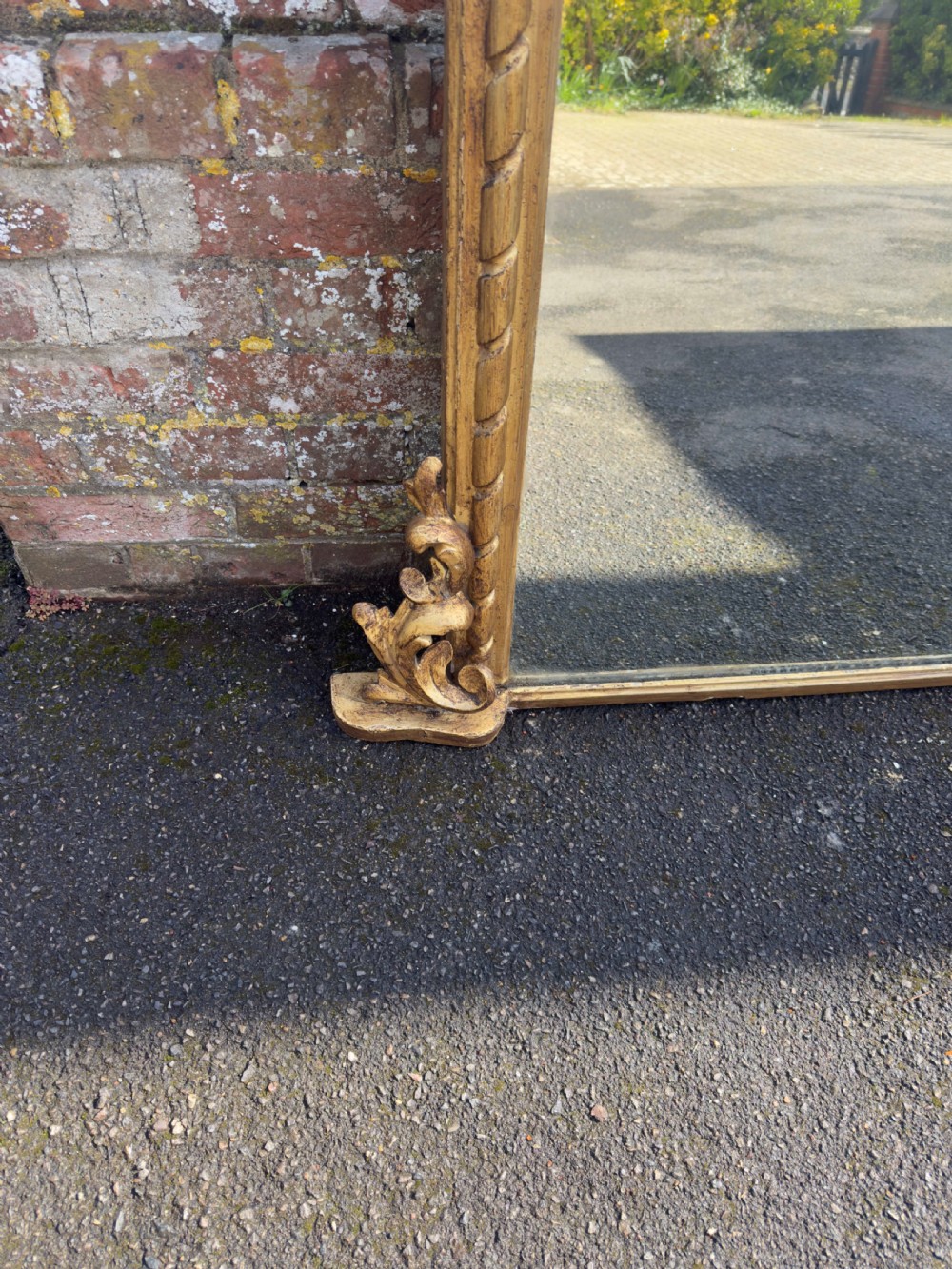 A nineteenth-century giltwood overmantel mirror with detailed gesso moulding, corner spandrels, and a central carved floral cresting. View V