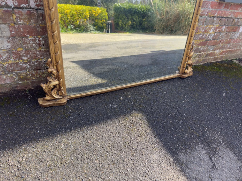 A nineteenth-century giltwood overmantel mirror with detailed gesso moulding, corner spandrels, and a central carved floral cresting. View VIII