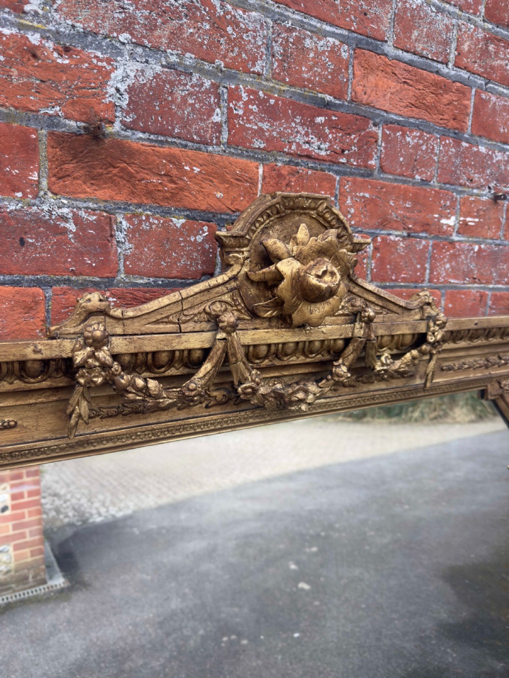 A nineteenth-century giltwood overmantel mirror with detailed gesso moulding, corner spandrels, and a central carved floral cresting. View IX