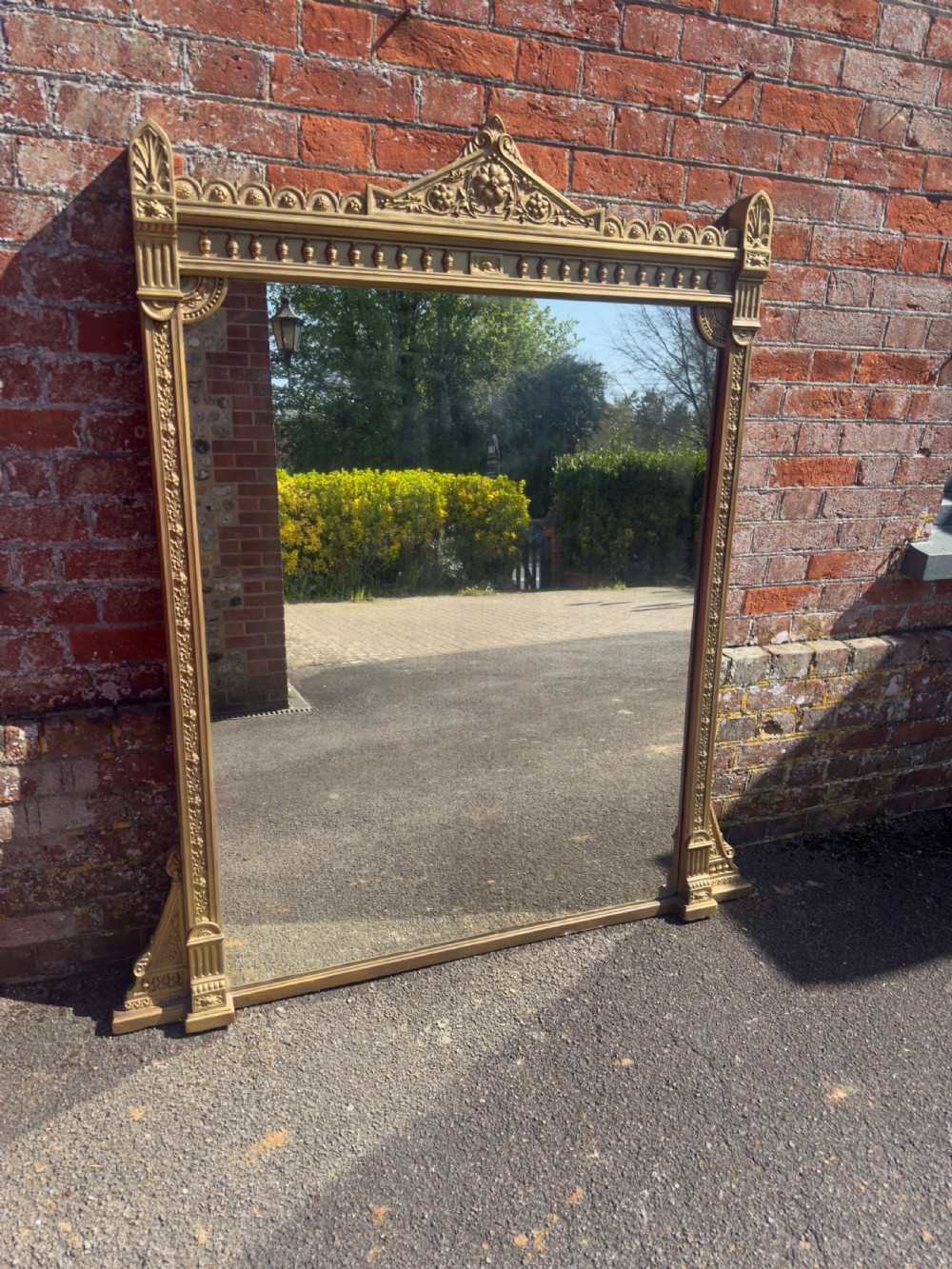 A large 19th-century rectangular giltwood overmantel mirror featuring a carved pediment with a lion mask crest and fluted side pilasters.