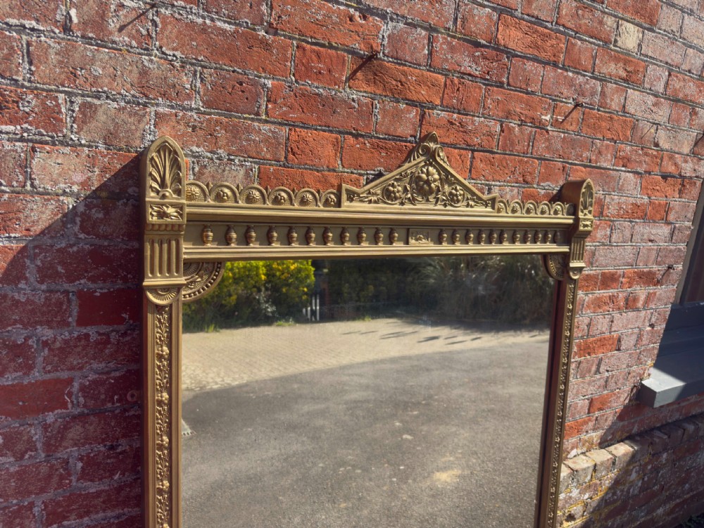 A large 19th-century rectangular giltwood overmantel mirror featuring a carved pediment with a lion mask crest and fluted side pilasters. View IV