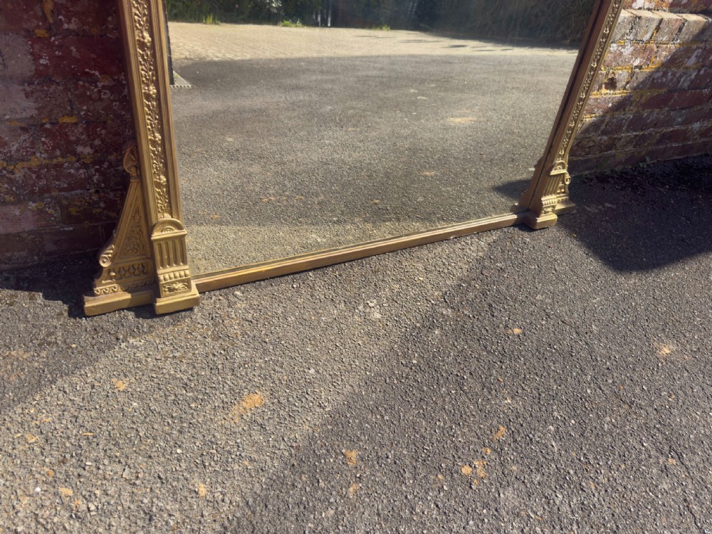A large 19th-century rectangular giltwood overmantel mirror featuring a carved pediment with a lion mask crest and fluted side pilasters. View VI