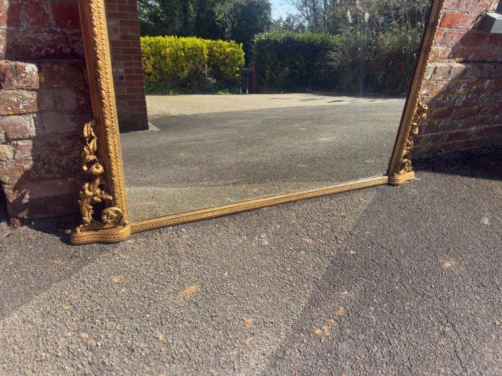 A large nineteenth-century rectangular giltwood overmantel mirror featuring ornate cresting with a bird motif and scrolled foliate moulding along the frame. View V