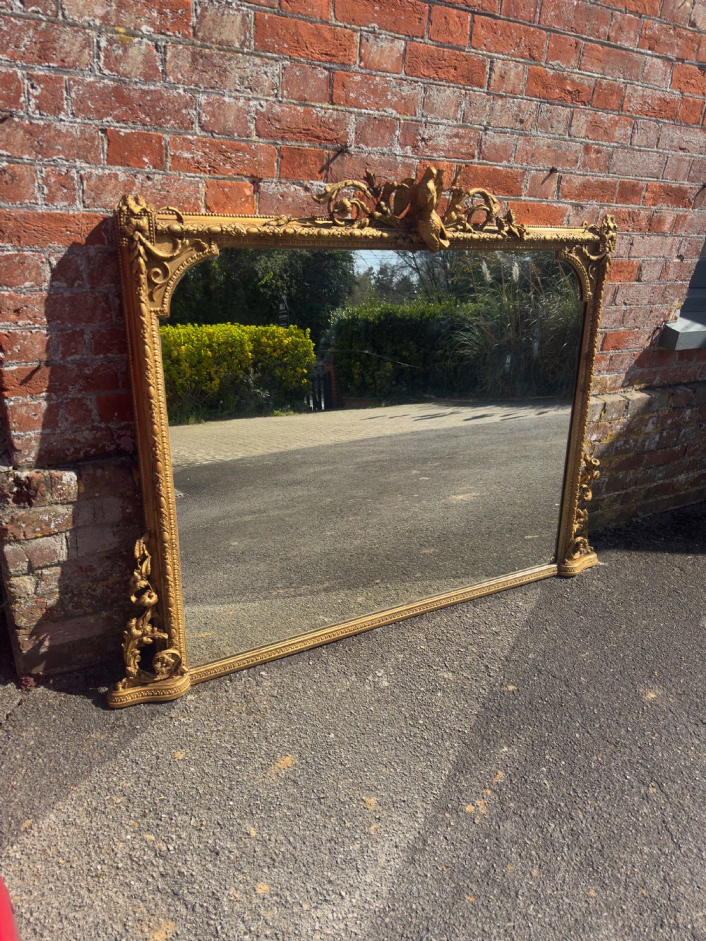 A large nineteenth-century rectangular giltwood overmantel mirror featuring ornate cresting with a bird motif and scrolled foliate moulding along the frame. View VIII