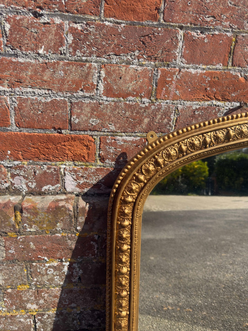 A 19th-century Victorian arched overmantel mirror featuring a gilded wood and gesso frame with carved bead detailing and ornate side flourishes. View IV