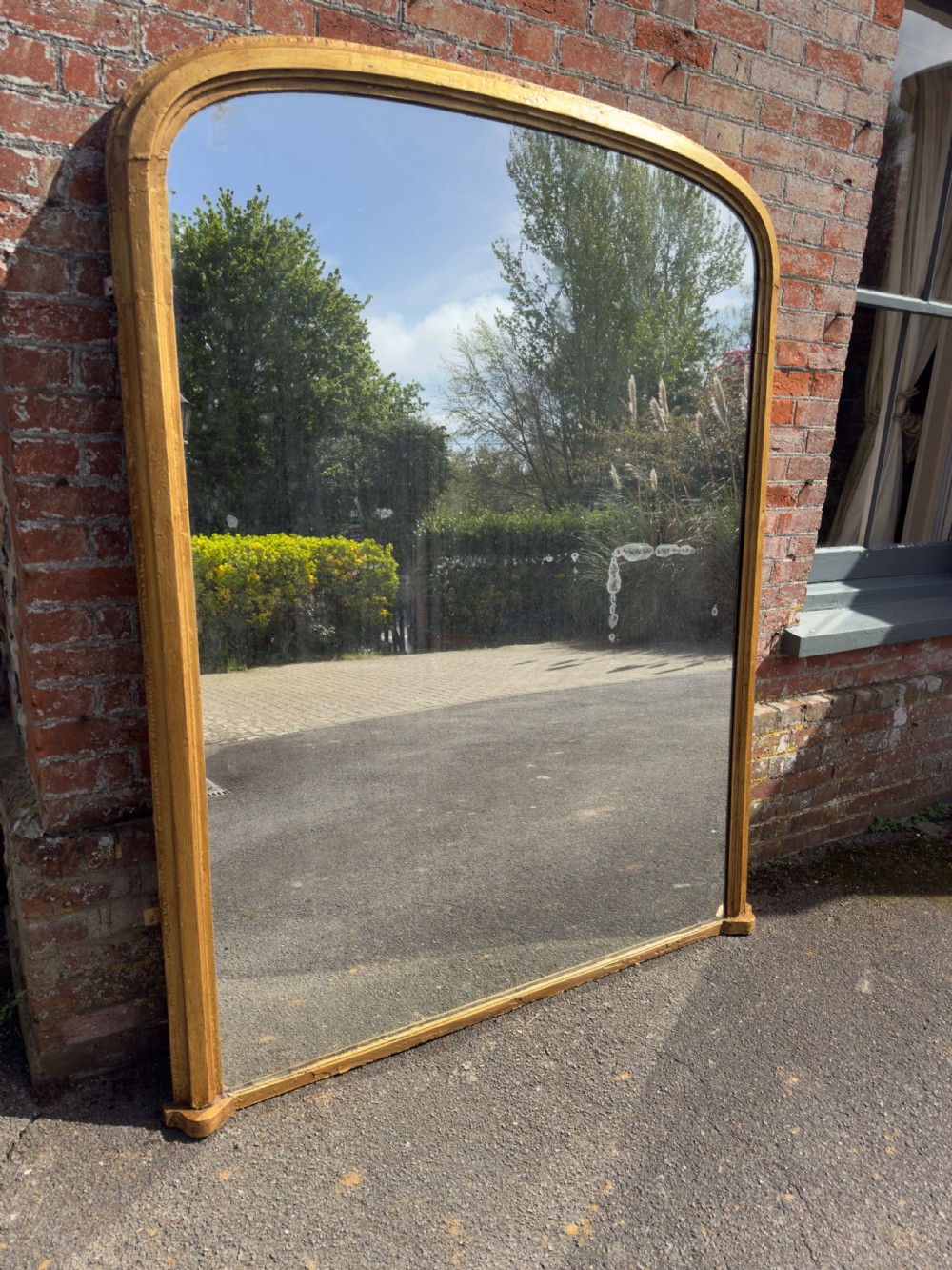 A large 19th-century arched overmantel mirror featuring a gilded wood and gesso frame with rounded top corners and subtle moulding details.
