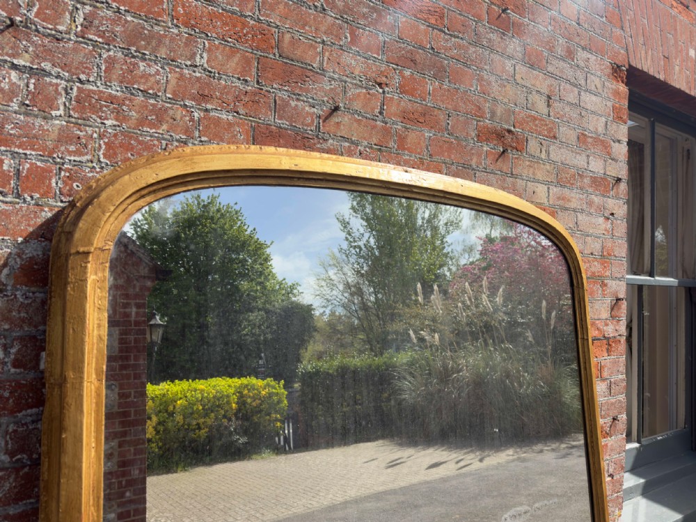 A large 19th-century arched overmantel mirror featuring a gilded wood and gesso frame with rounded top corners and subtle moulding details. View II