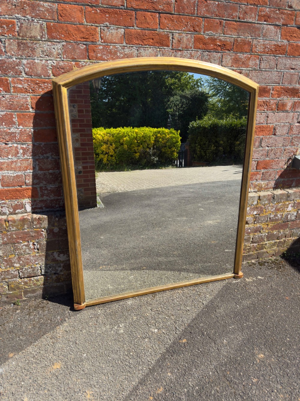 A large nineteenth-century English overmantel mirror featuring a gilded wood and gesso frame with an arched top and moulded edges.