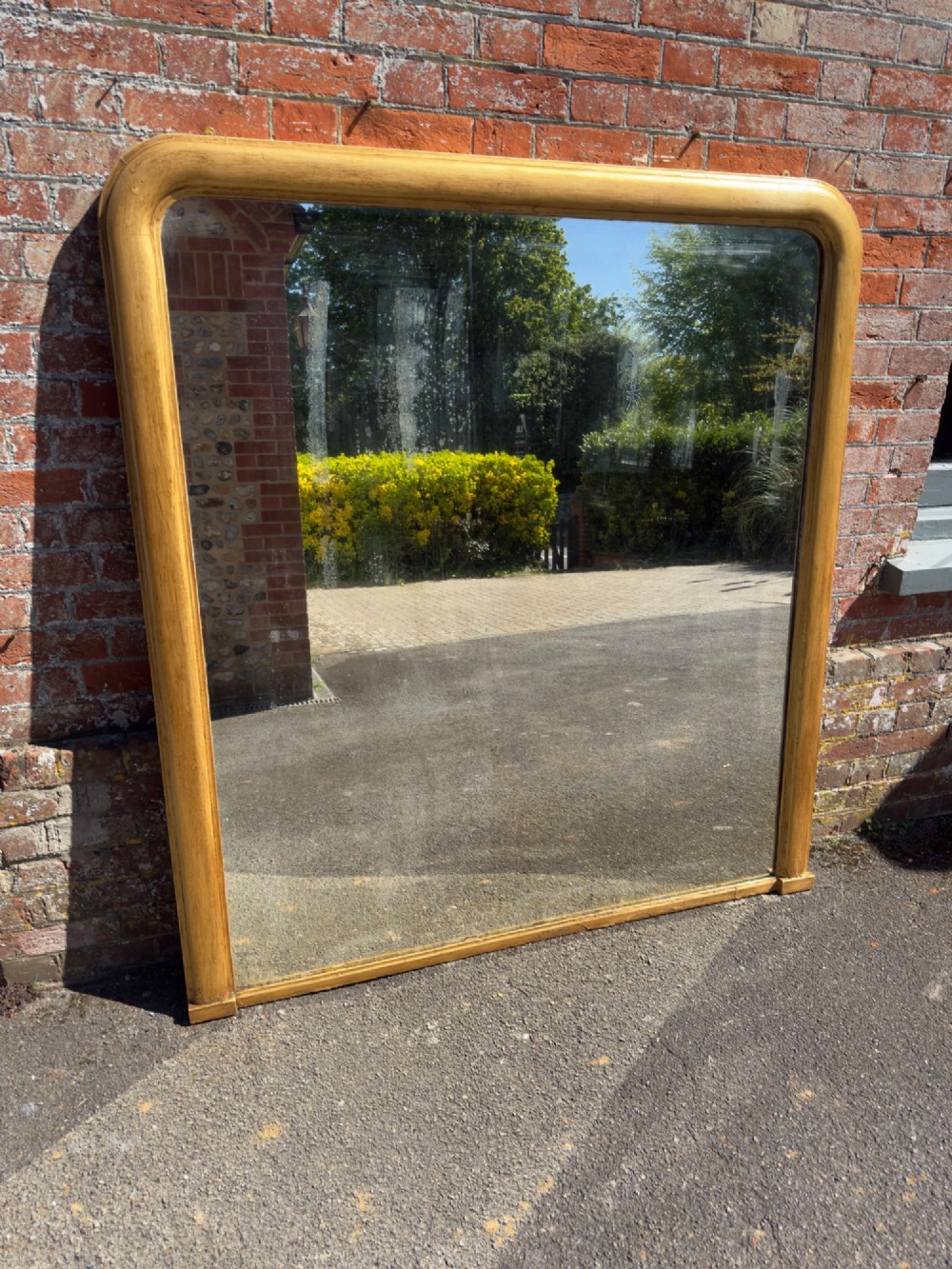 A large nineteenth-century English giltwood overmantel mirror featuring an arched top and rounded upper shoulders.