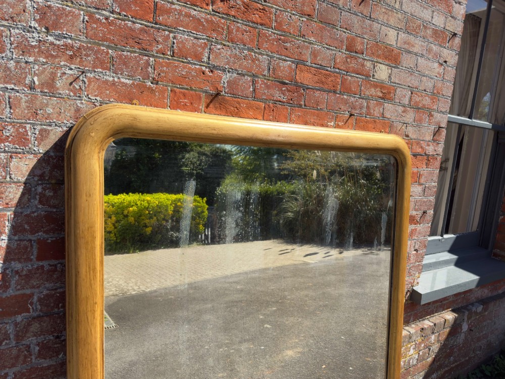 A large nineteenth-century English giltwood overmantel mirror featuring an arched top and rounded upper shoulders. View III
