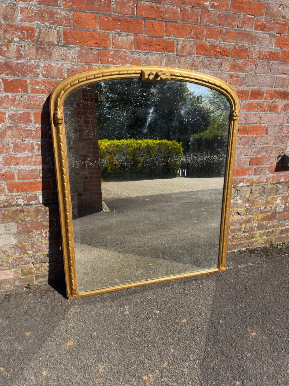A 19th-century arched overmantel mirror featuring a gold giltwood rope-twist frame and original foxed glass.