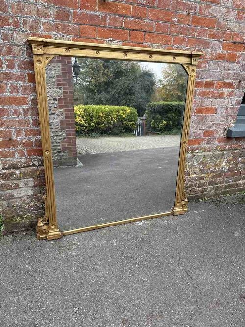 A large 19th-century English giltwood overmantel mirror featuring ribbed pilasters and rosette carvings around a rectangular mirror glass plate. View V