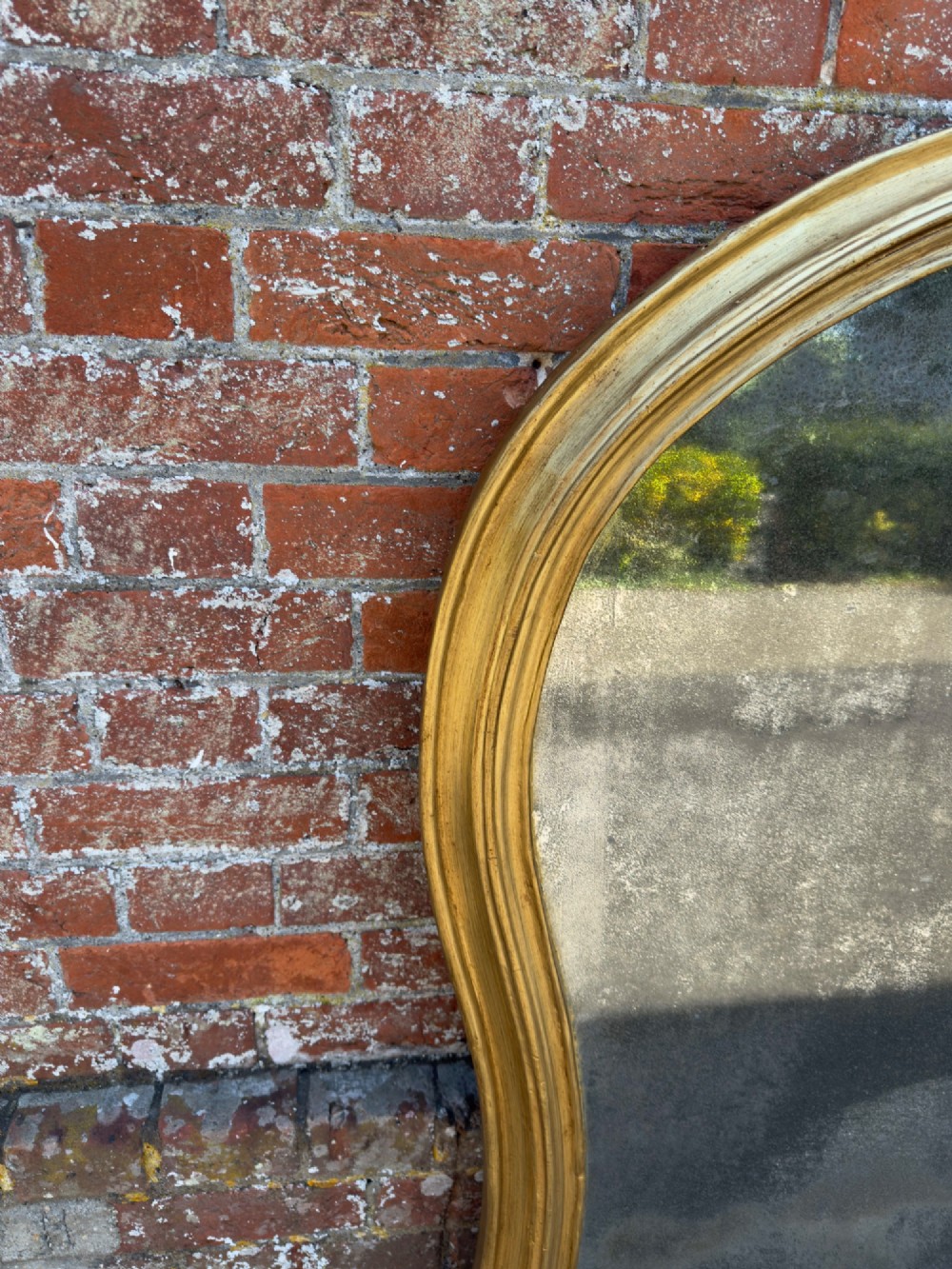 A 19th-century English giltwood overmantel mirror featuring an arched hourglass shape with small side foot supports. View II