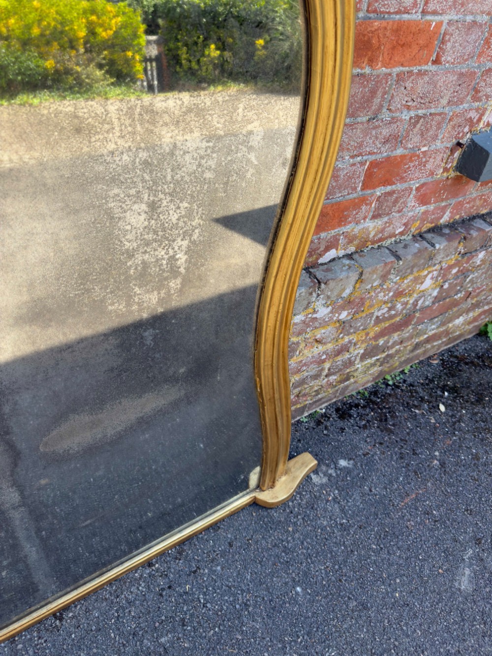 A 19th-century English giltwood overmantel mirror featuring an arched hourglass shape with small side foot supports. View IV