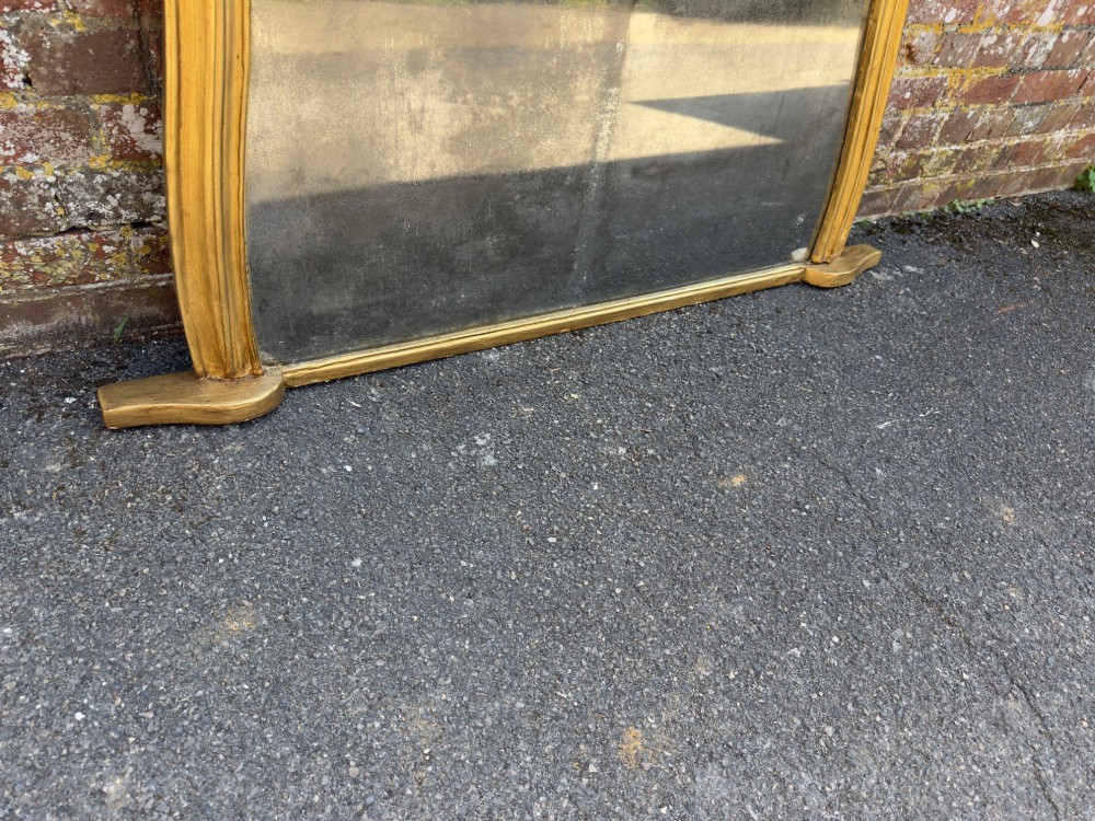 A 19th-century English giltwood overmantel mirror featuring an arched hourglass shape with small side foot supports. View V