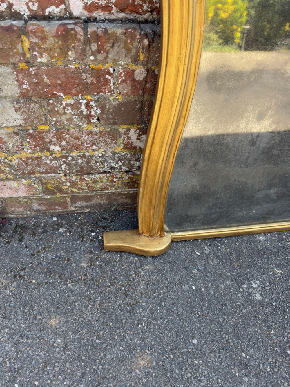 A 19th-century English giltwood overmantel mirror featuring an arched hourglass shape with small side foot supports. View VI