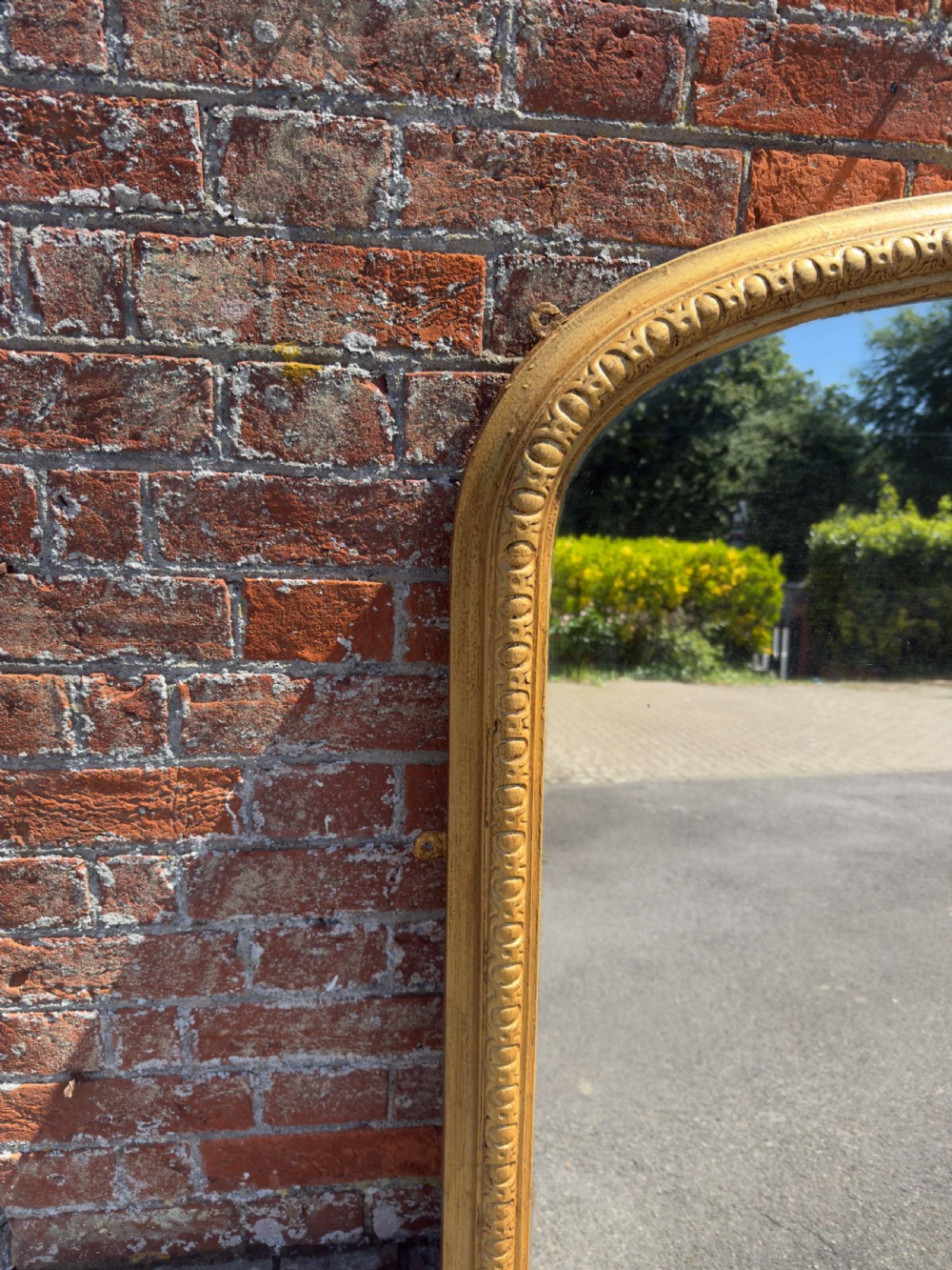 A 19th-century English giltwood overmantel mirror featuring an arched top frame and carved acanthus leaf details at the base. View IV