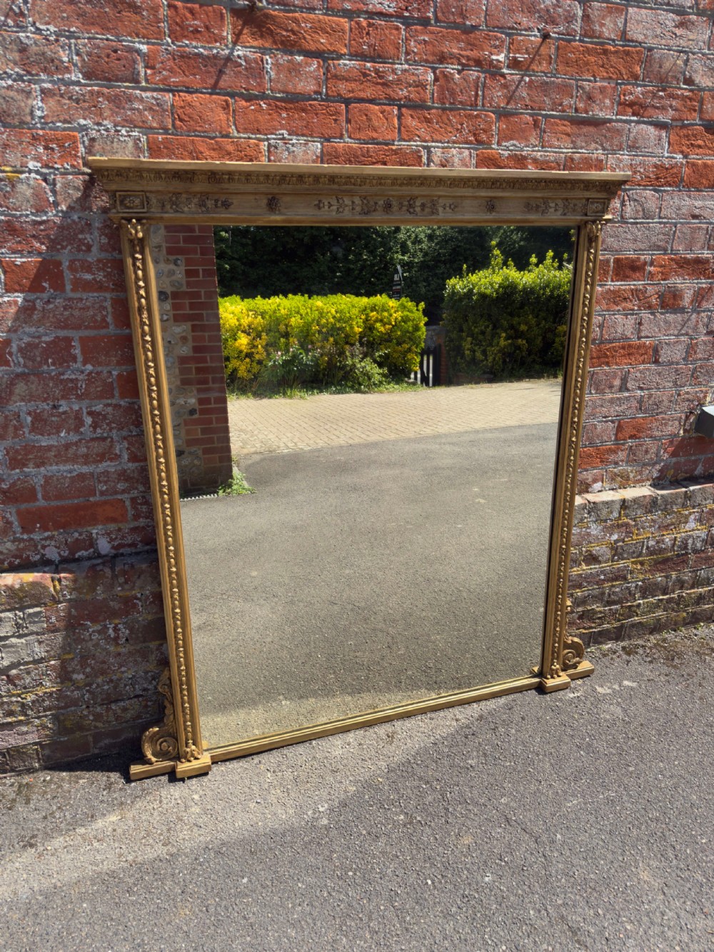 A large rectangular 19th-century giltwood overmantel mirror featuring egg-and-dart moulding along the upper frieze and scroll motifs at the lower edges.