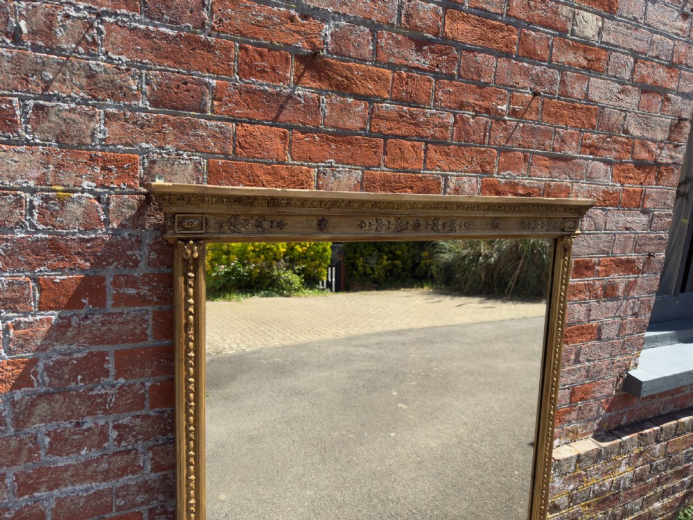 A large rectangular 19th-century giltwood overmantel mirror featuring egg-and-dart moulding along the upper frieze and scroll motifs at the lower edges. View III