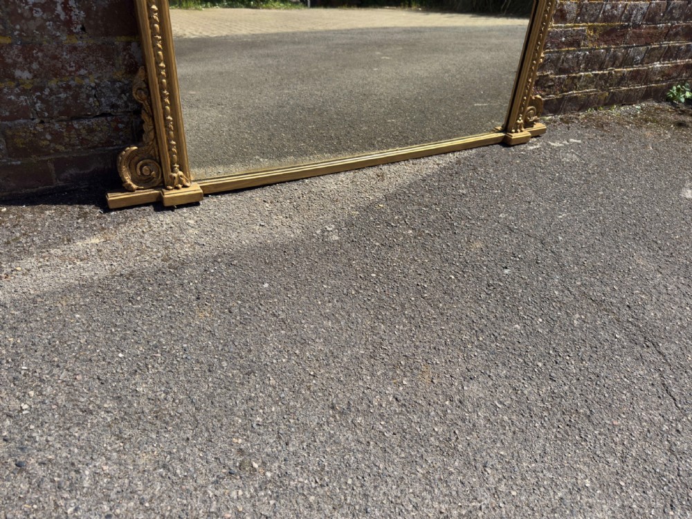 A large rectangular 19th-century giltwood overmantel mirror featuring egg-and-dart moulding along the upper frieze and scroll motifs at the lower edges. View VI