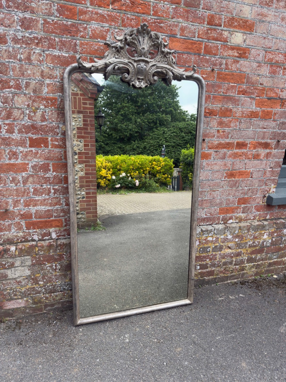 A tall 19th-century French arched mirror with a carved foliate gesso crest and aged silver leaf finish. View VII
