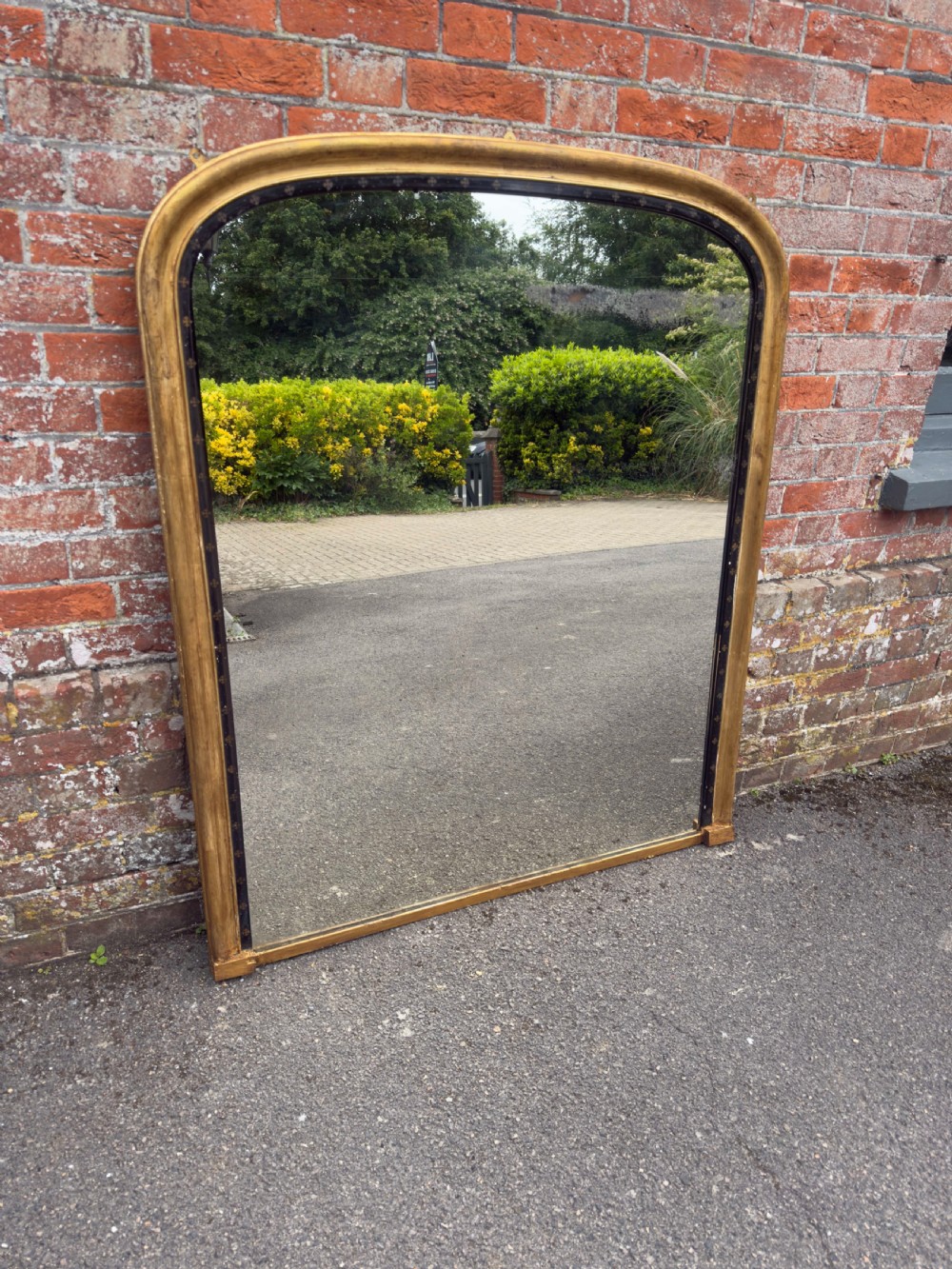 A large Victorian arched overmantel mirror featuring a gilded wood frame with a dark inner border detailing. View VII