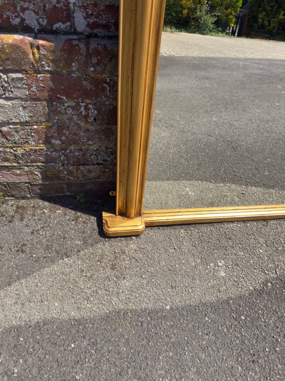 An antique 19th-century English gilt carved wood overmantel mirror featuring a serpentine arched cresting and moulded frame. View III