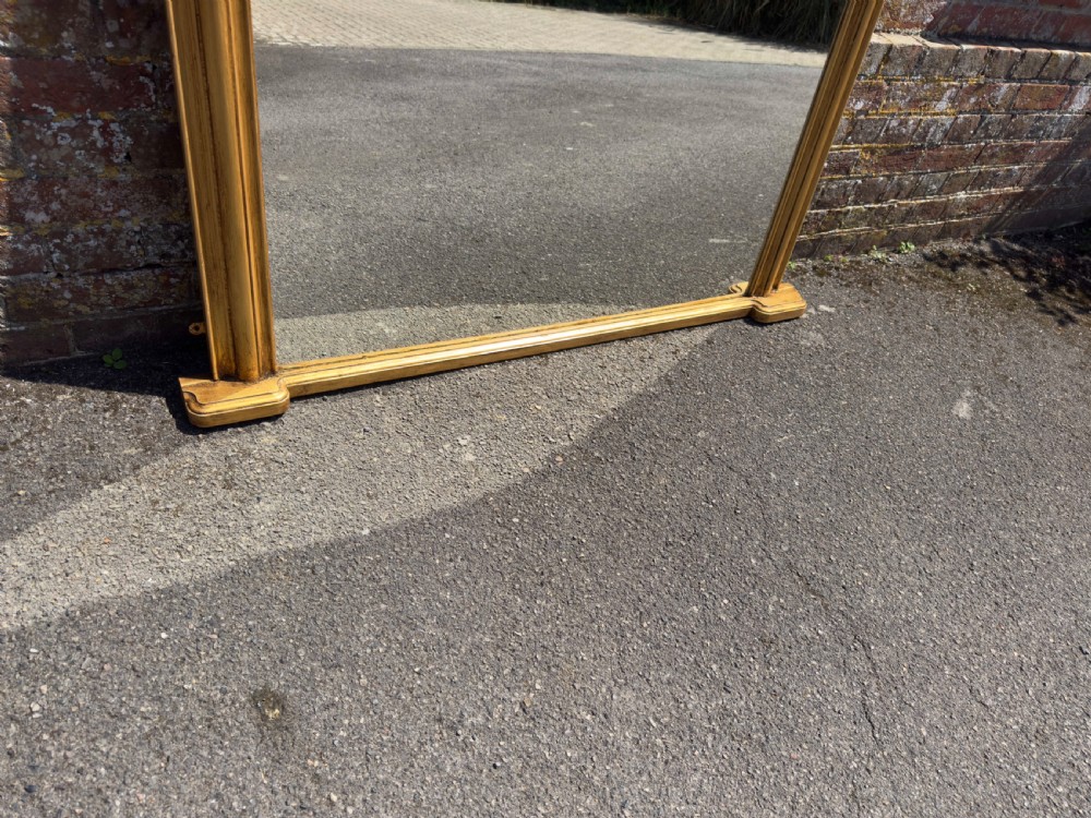 An antique 19th-century English gilt carved wood overmantel mirror featuring a serpentine arched cresting and moulded frame. View IV