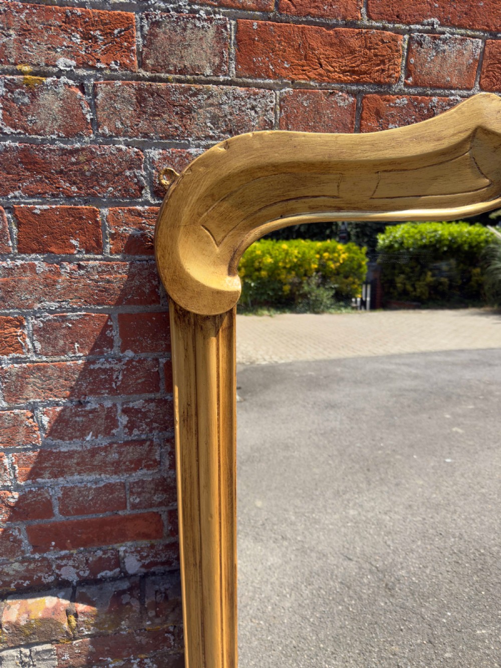 An antique 19th-century English gilt carved wood overmantel mirror featuring a serpentine arched cresting and moulded frame. View V