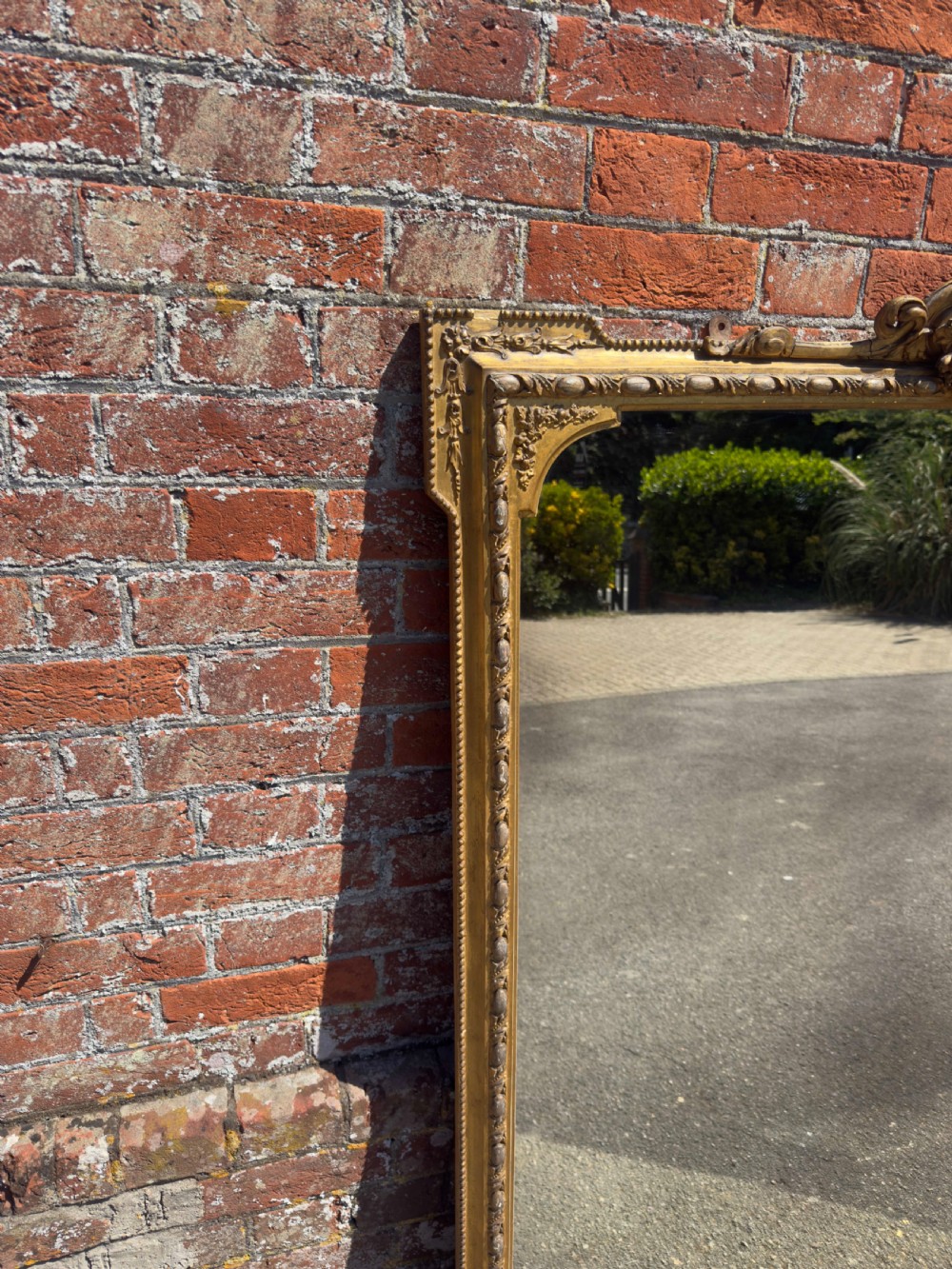 A large 19th-century English giltwood and gesso overmantel mirror featuring an ornate carved central crest, moulded frame, and scrolled side feet. View IV