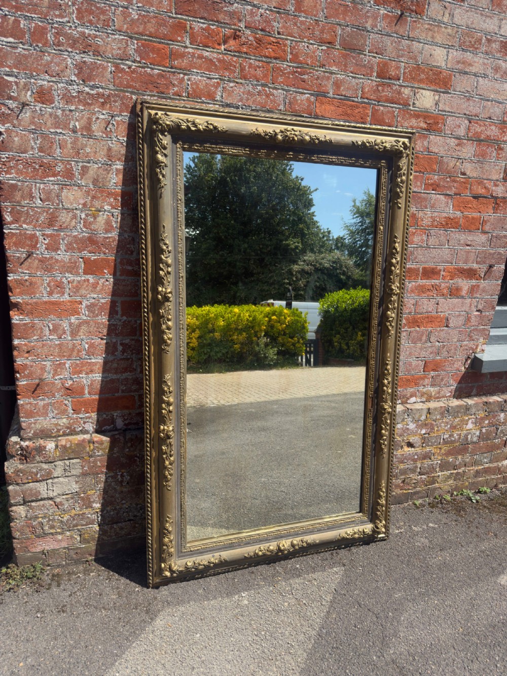 A large 19th-century rectangular French mirror featuring an ornate gilded gesso frame with detailed floral and leaf mouldings.