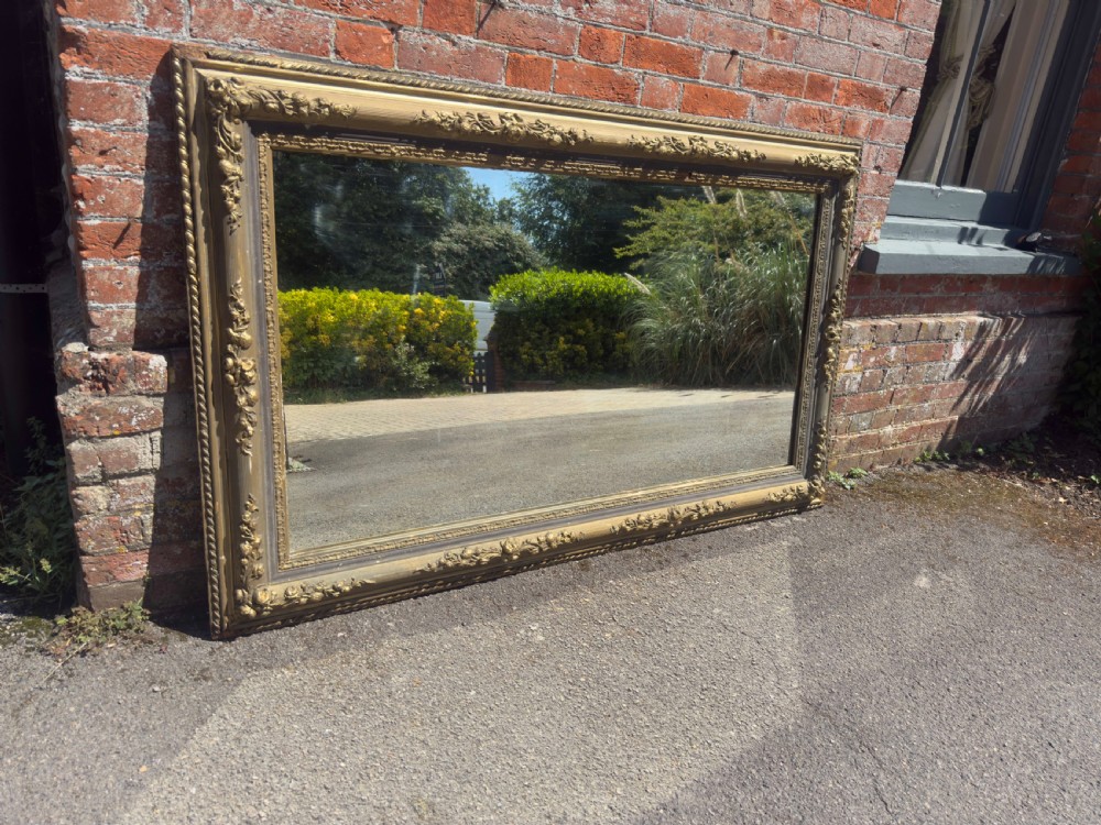 A large 19th-century rectangular French mirror featuring an ornate gilded gesso frame with detailed floral and leaf mouldings. View II