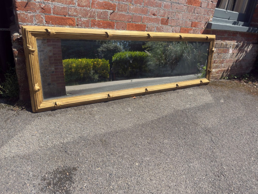 A large rectangular antique English pier mirror featuring a reeded giltwood frame embellished with carved leaf clasp accents.