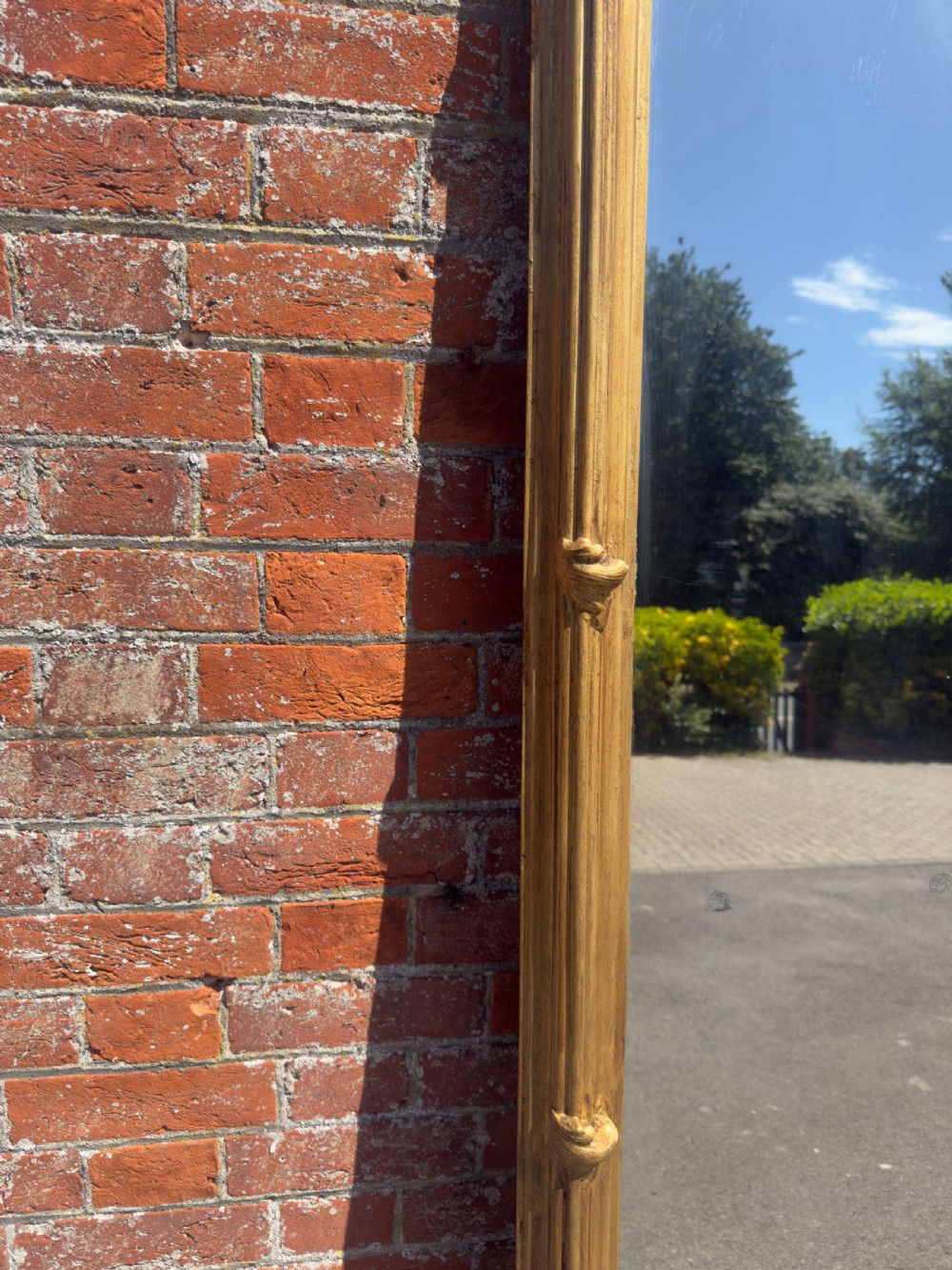 A large rectangular antique English pier mirror featuring a reeded giltwood frame embellished with carved leaf clasp accents. View IV