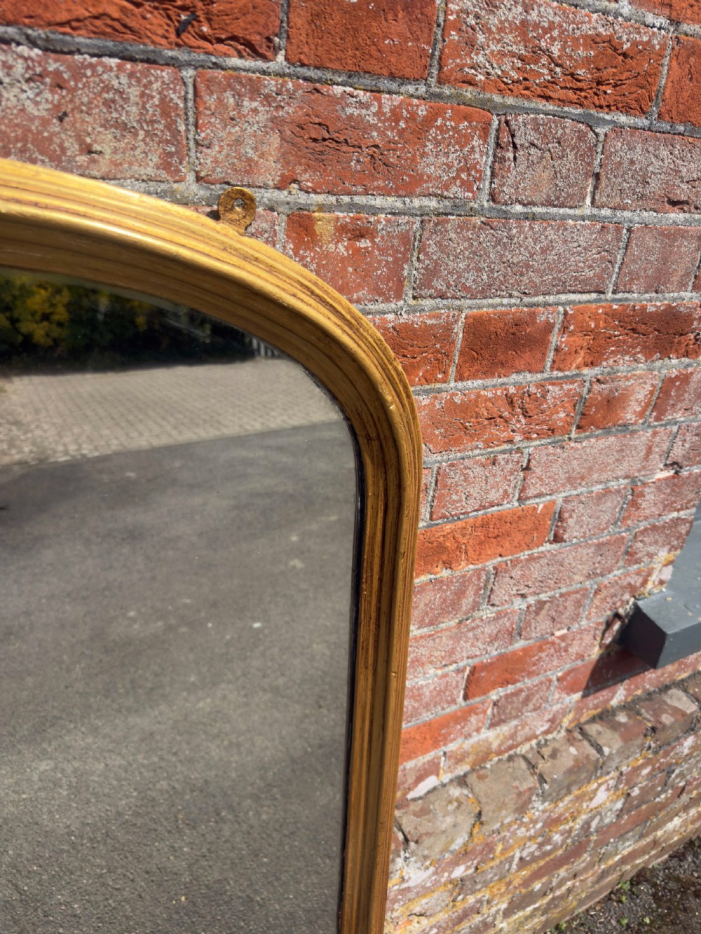 A 19th-century arched overmantel mirror featuring a gilded carved wood frame with integrated side support feet. View II