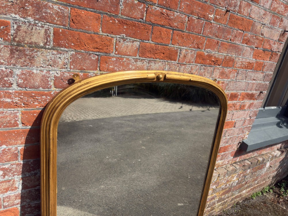 A 19th-century arched overmantel mirror featuring a gilded carved wood frame with integrated side support feet. View IV