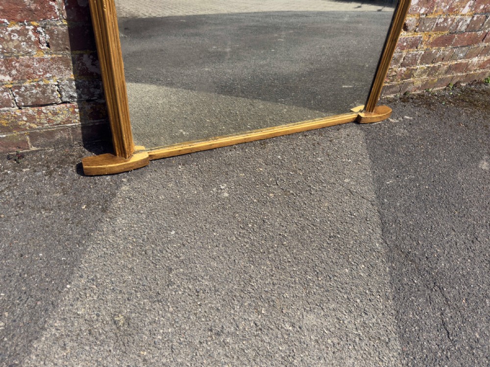 A 19th-century arched overmantel mirror featuring a gilded carved wood frame with integrated side support feet. View VI