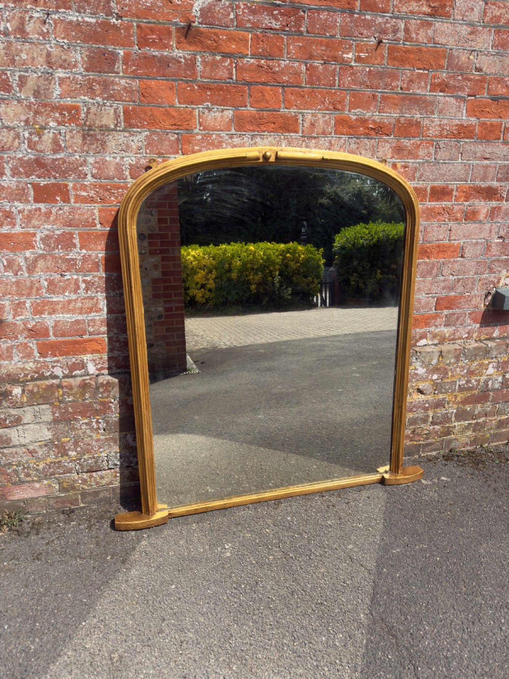 A 19th-century arched overmantel mirror featuring a gilded carved wood frame with integrated side support feet. View VIII