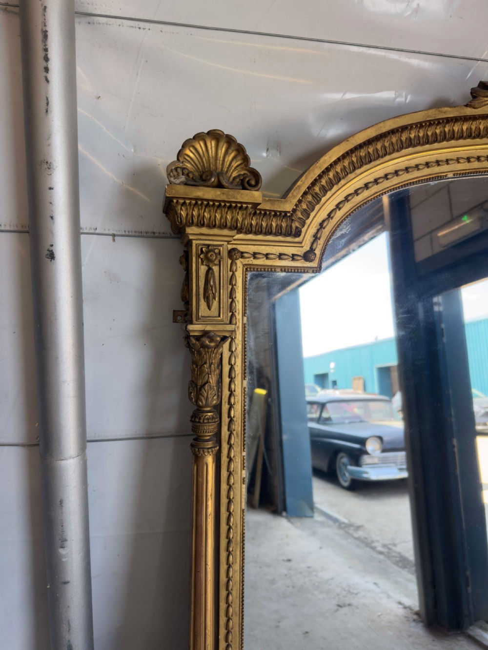 A large 19th-century gilded overmantel mirror featuring an arched top, carved crest with foliage, and decorative pilaster sides. View III