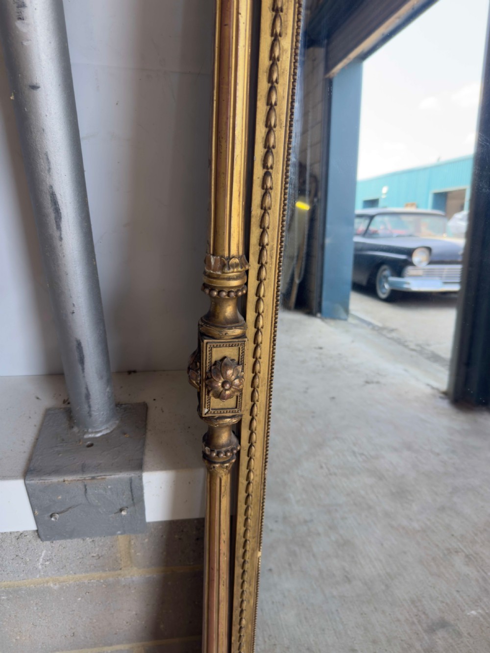 A large 19th-century gilded overmantel mirror featuring an arched top, carved crest with foliage, and decorative pilaster sides. View IV