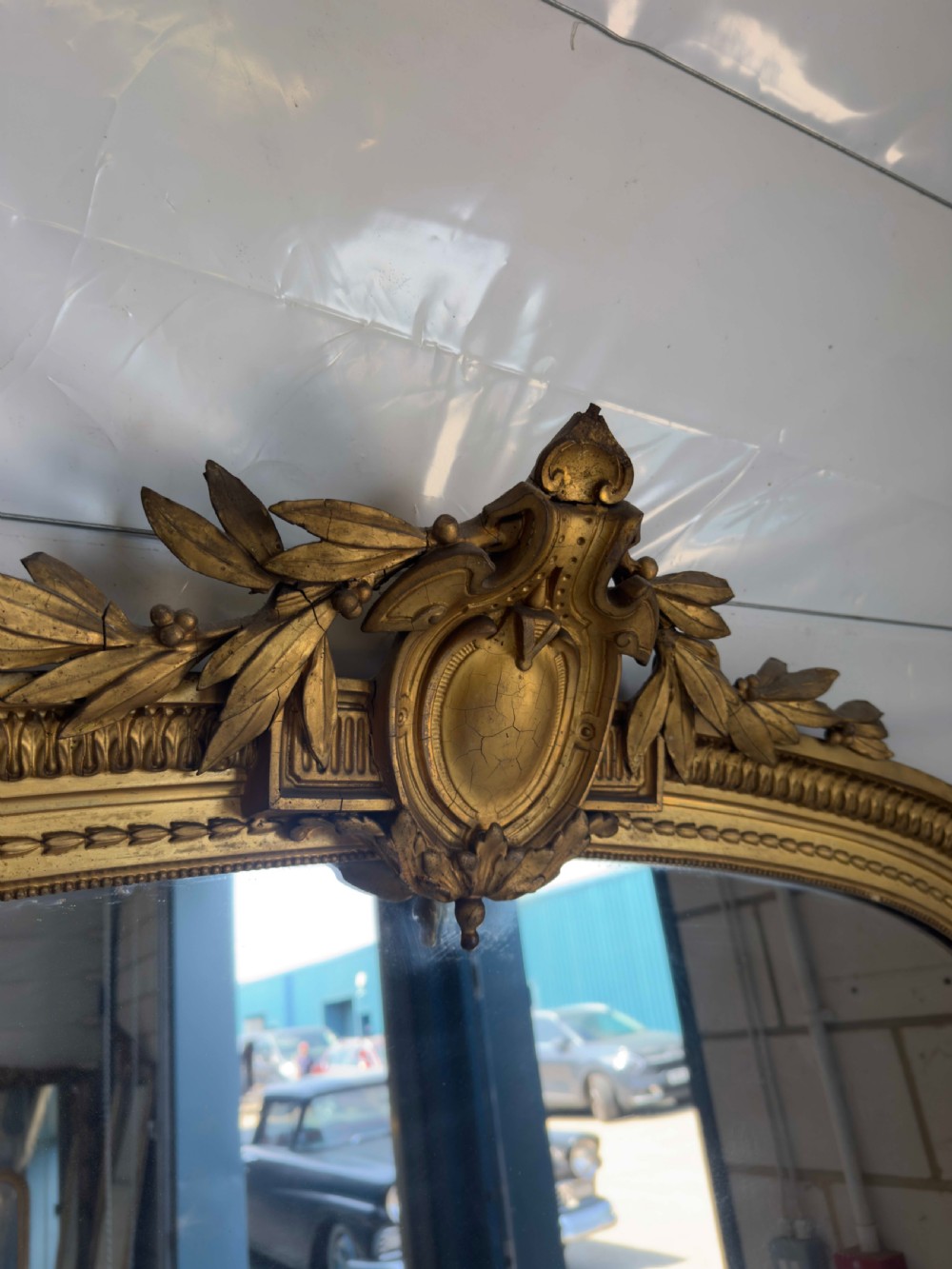 A large 19th-century gilded overmantel mirror featuring an arched top, carved crest with foliage, and decorative pilaster sides. View VII