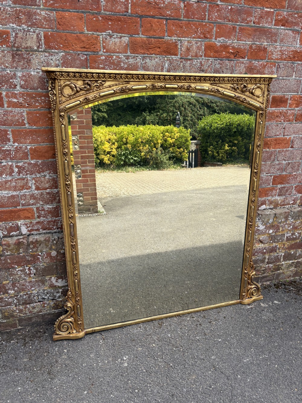 A large 19th-century Victorian arched giltwood and gesso overmantel mirror with ornamental mouldings and scrolled side brackets. View VI