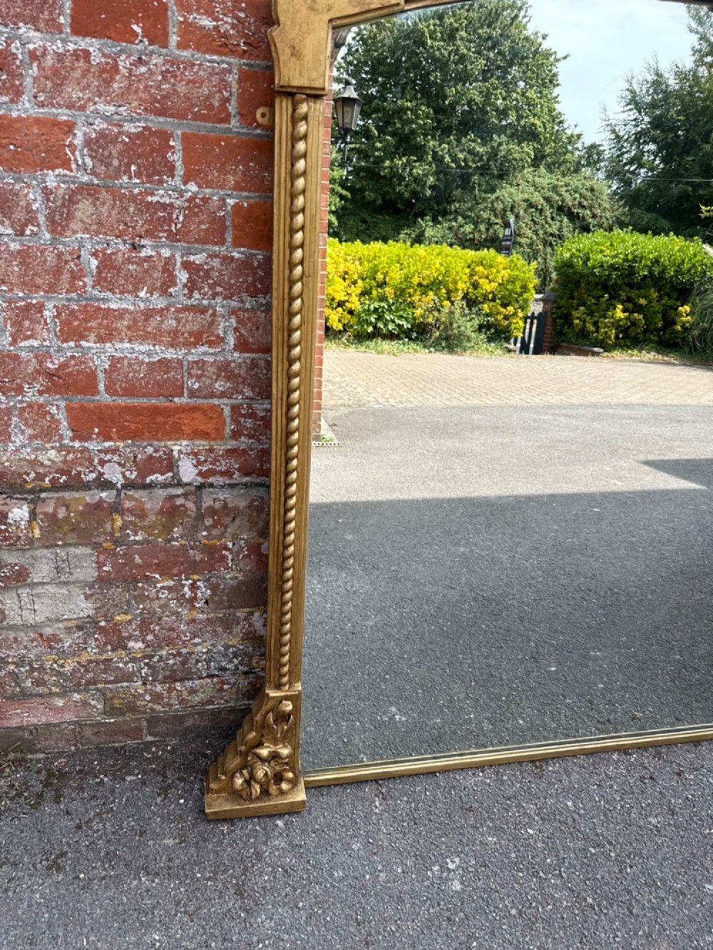 A large 19th-century overmantel mirror featuring a gilded wood frame with a central floral crest, rope-twist side columns, and an arched top. View II