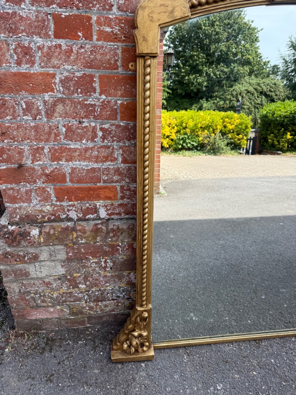 A large 19th-century overmantel mirror featuring a gilded wood frame with a central floral crest, rope-twist side columns, and an arched top. View VII