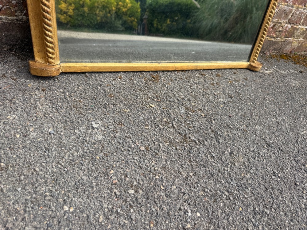 A large 19th-century gilded wood and gesso mirror with an arched top, ribbed frame, and decorative corner embellishments. View V